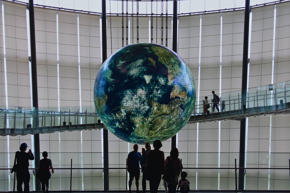 Families and children silhouetted in front of the giant Earth globe display at Tokyo’s Miraikan science museum.