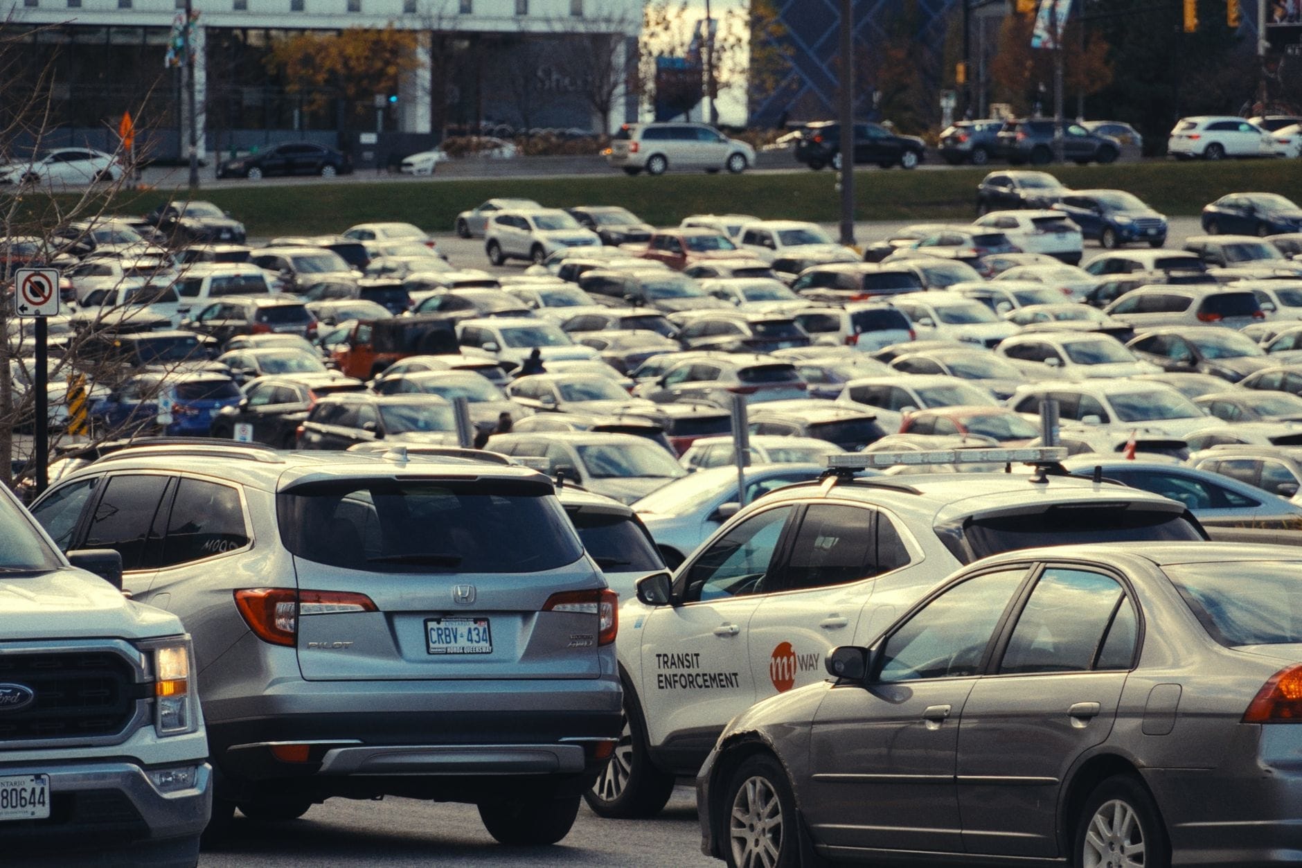 Estacionamento de aeroporto lotado com carros em frente aos terminais. Alguns veículos têm placas de Ontario, sugerindo uma localização canadense.