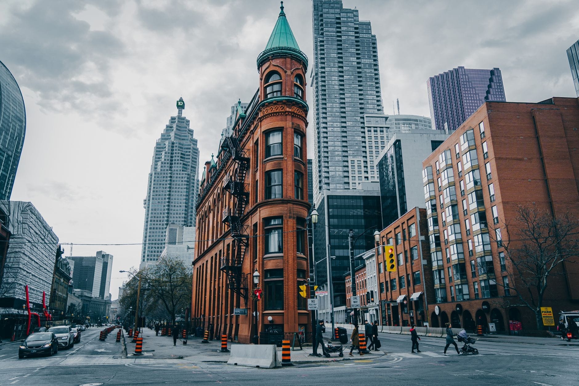 O Gooderham Building com arranha-céus modernos no centro de Toronto, ilustrando a evolução arquitetônica da cidade ao longo das eras.