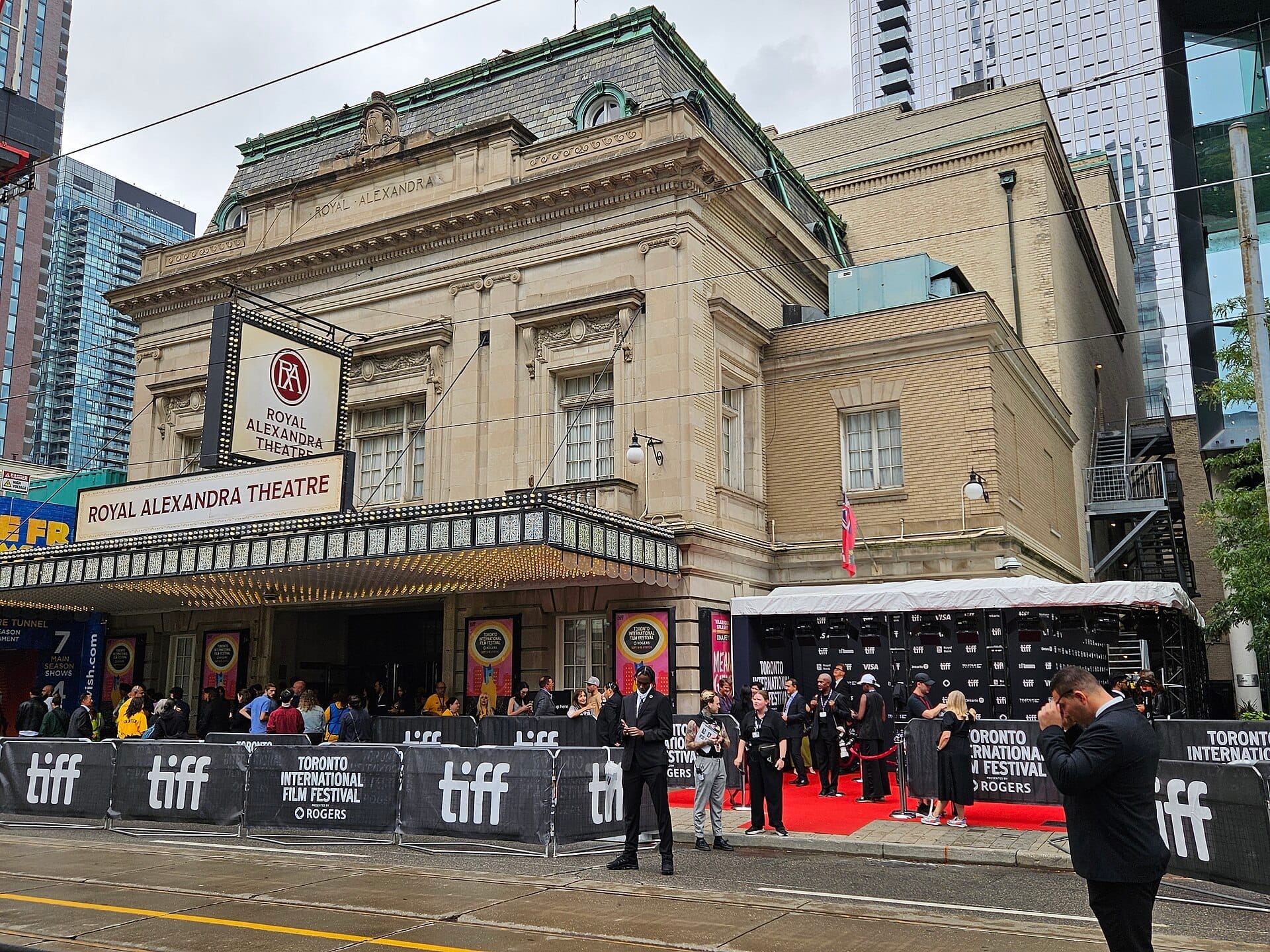 Multidões se reúnem do lado de fora do histórico Royal Alexandra Theatre em Toronto durante o Toronto International Film Festival, com sinalização do festival e um tapete vermelho.