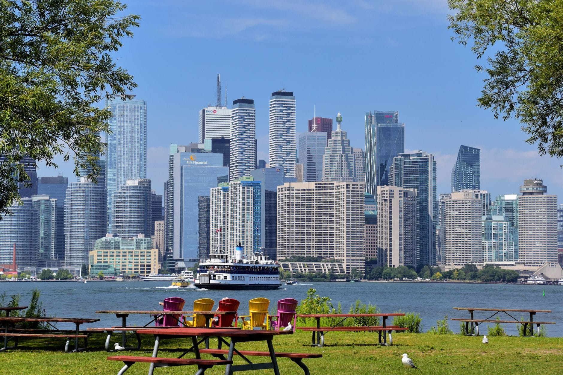 Vista do skyline de Toronto com cadeiras coloridas e mesas de piquenique em primeiro plano, visto das Ilhas Toronto em um dia claro.