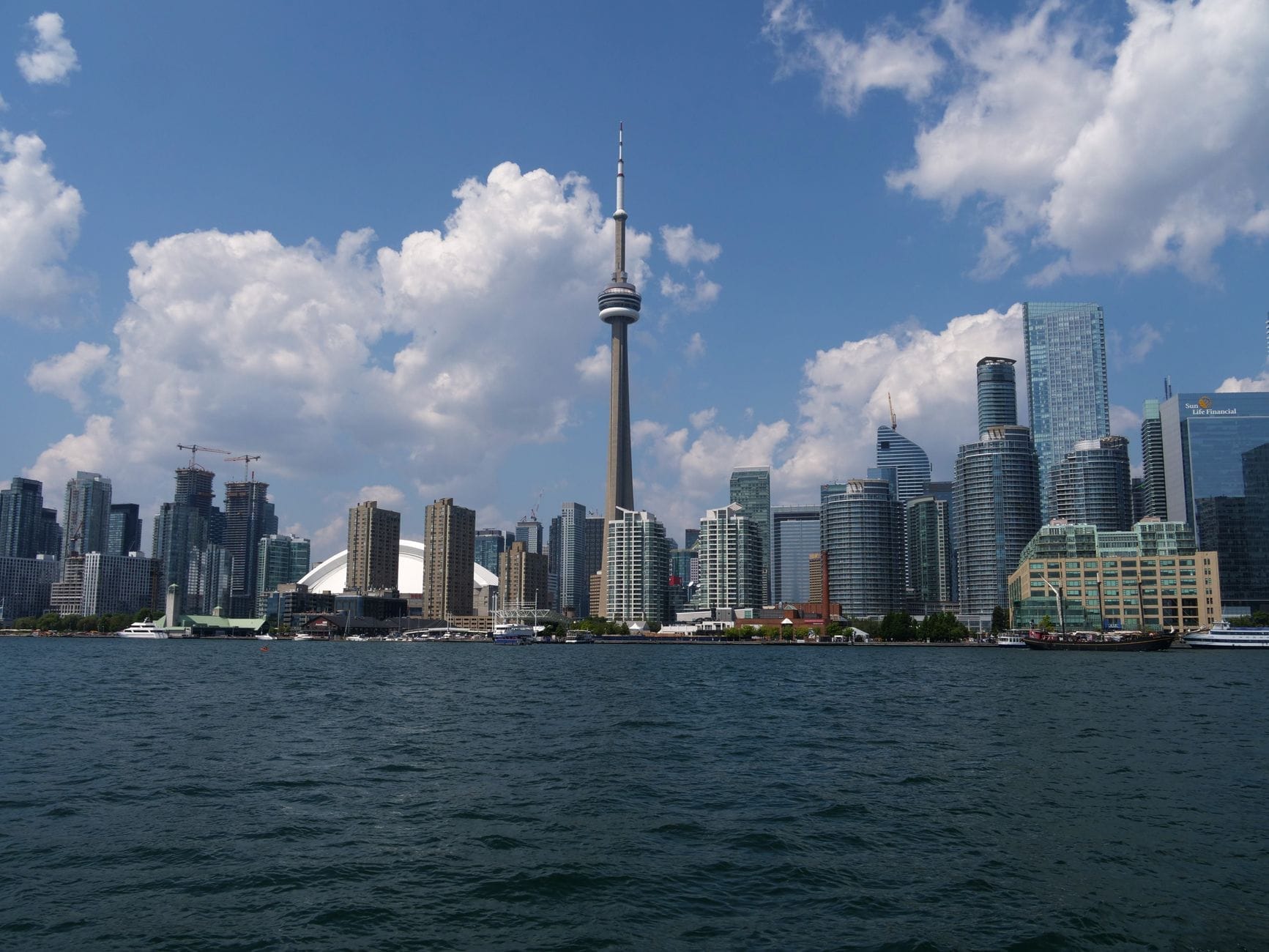 Vista diurna e luminosa da orla de Toronto com a CN Tower, o Rogers Centre e hotéis modernos, ideal para estadas em família perto das principais atrações.