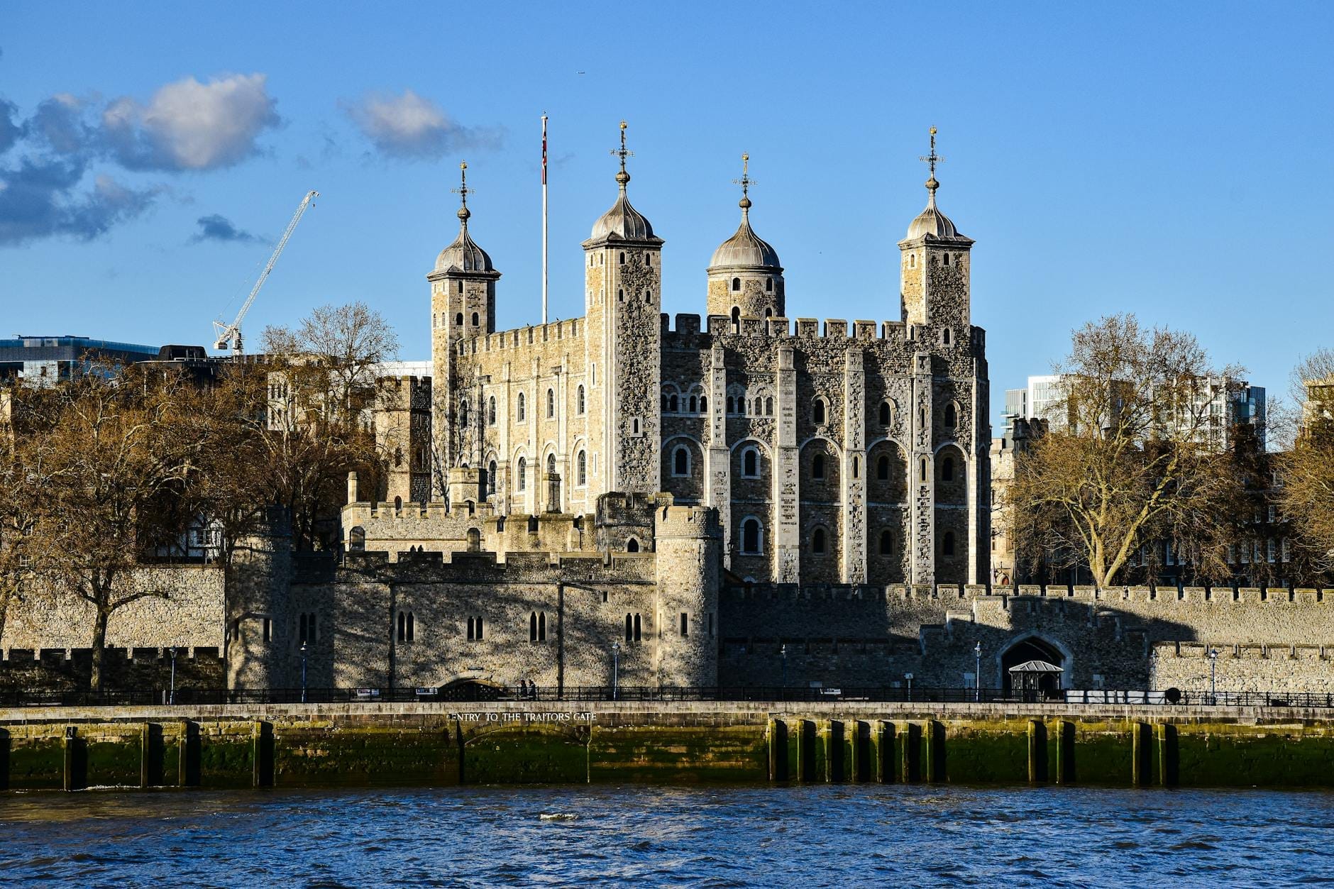 La Torre di Londra vista dall'altra riva del Tamigi in una giornata di sole, con cielo azzurro e limpido, che cattura la fortezza con le sue iconiche torrette.
