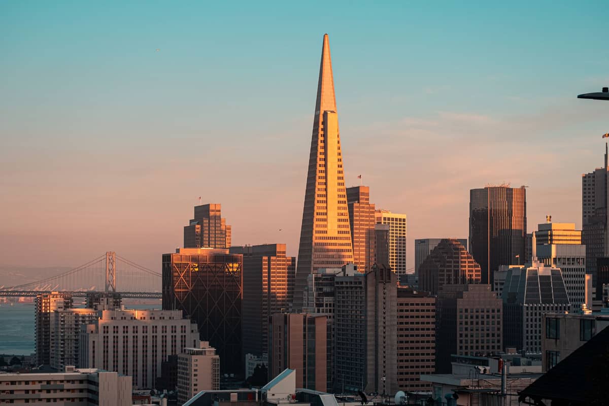 El horizonte de San Francisco al atardecer con la Pirámide Transamerica destacando en el centro y el Bay Bridge al fondo.
