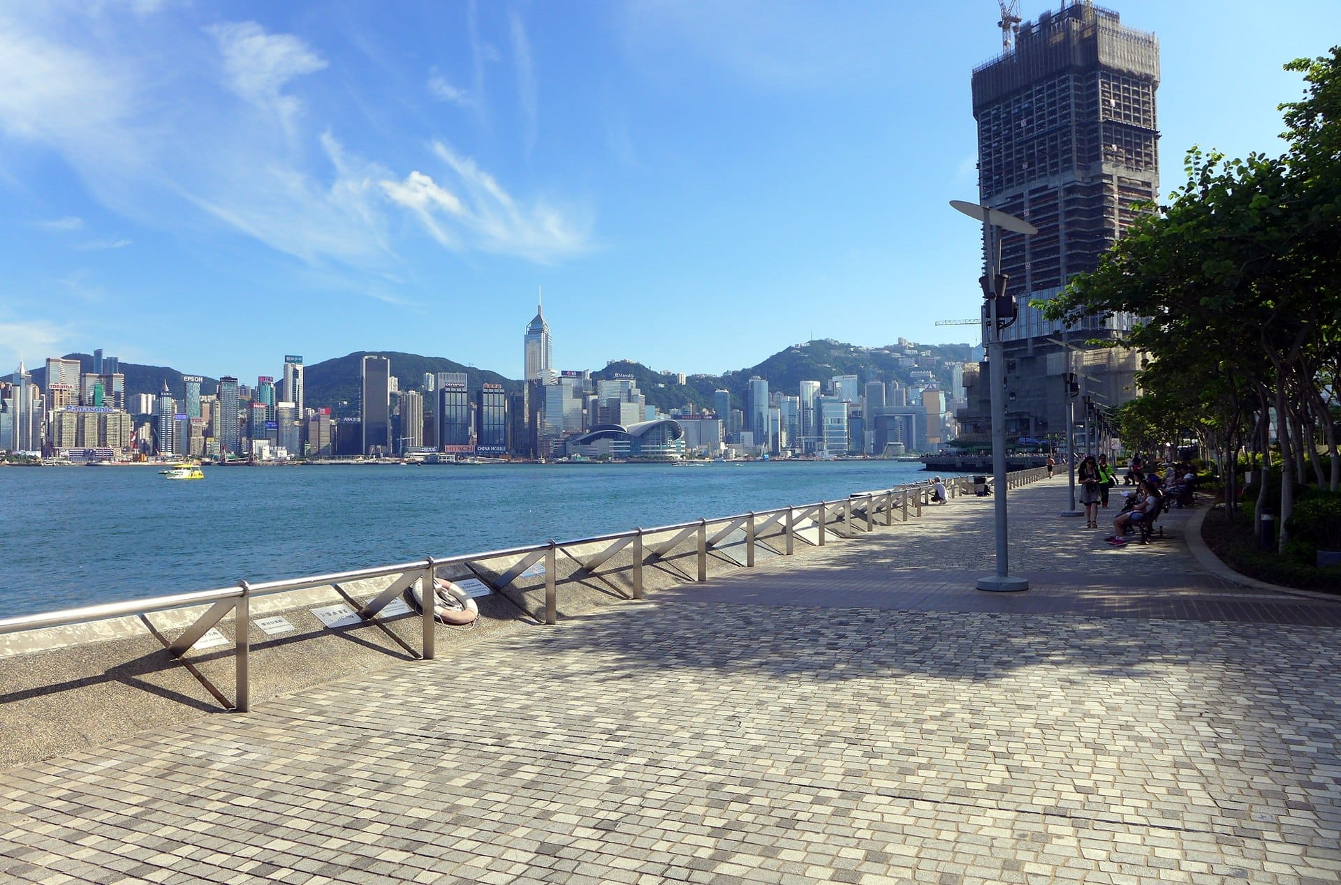 Tsim Sha Tsui Promenade con vista sul Victoria Harbour e le iconiche torri dello skyline di Hong Kong.
