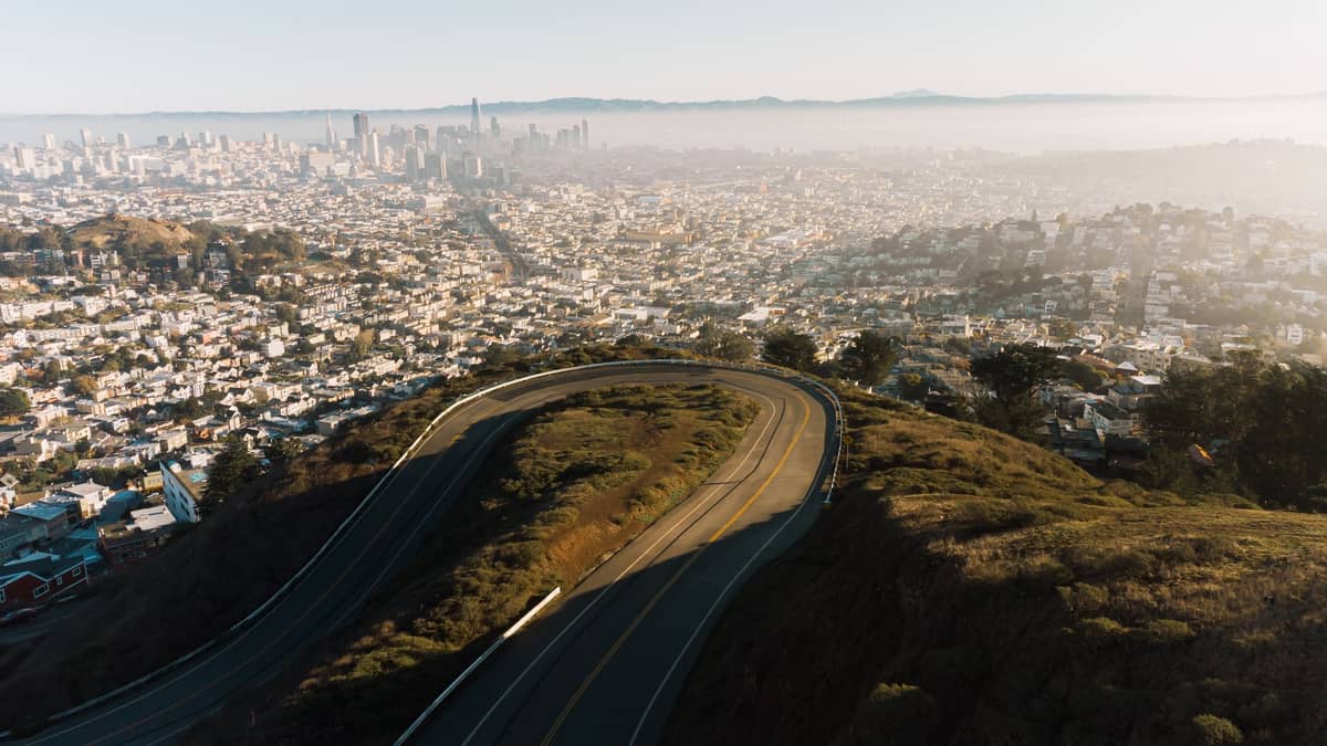 Vista panorámica desde Twin Peaks, San Francisco, con el sinuoso camino de la cima, el skyline de la ciudad y la lejana Bahía en un día despejado.
