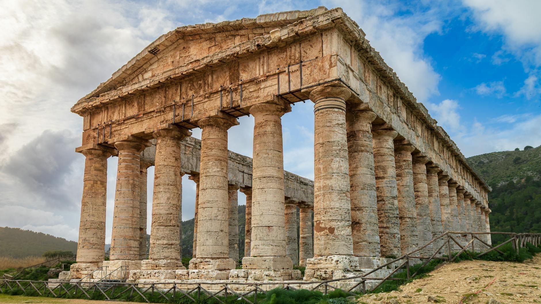 Weitwinkelansicht des antiken griechischen Segesta-Tempels, der isoliert auf einem Hügel im Westen Siziliens steht, mit dramatischem Himmel und der umliegenden Landschaft.