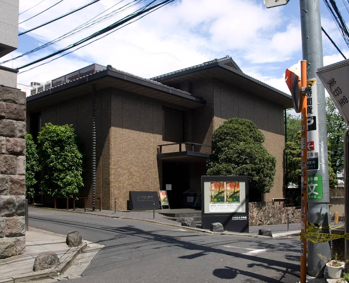 Exterior view of the Ukiyo-e Ota Memorial Museum of Art in Tokyo, showing its modern brick building framed by trees on a sunny day.