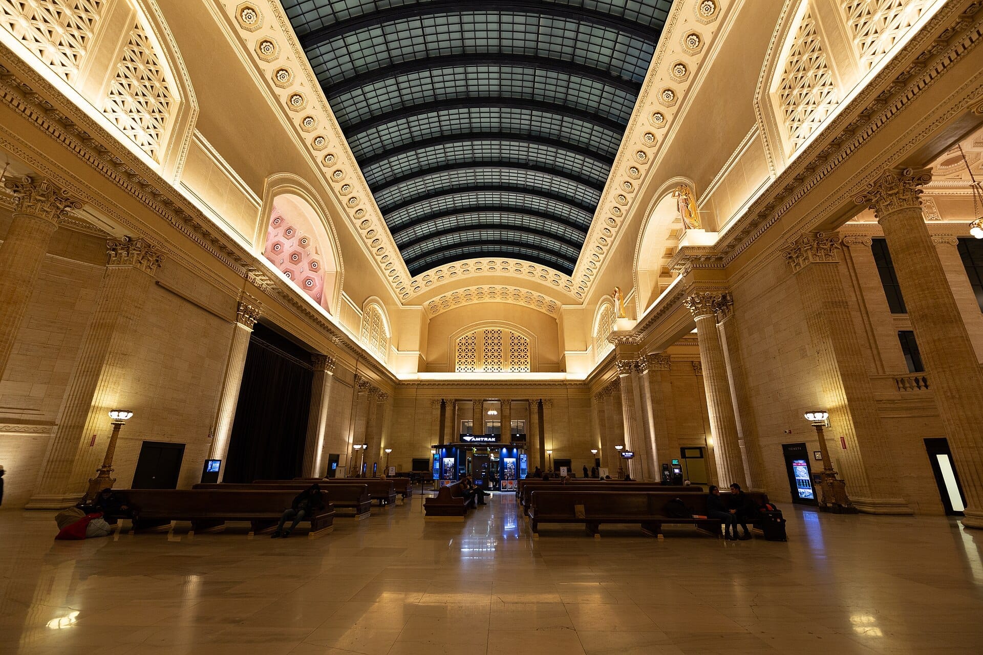 Vista grandangolare della Great Hall della Union Station a Chicago, con alte colonne di marmo, panchine e uno spettacolare lucernario a volta a botte in vetro.