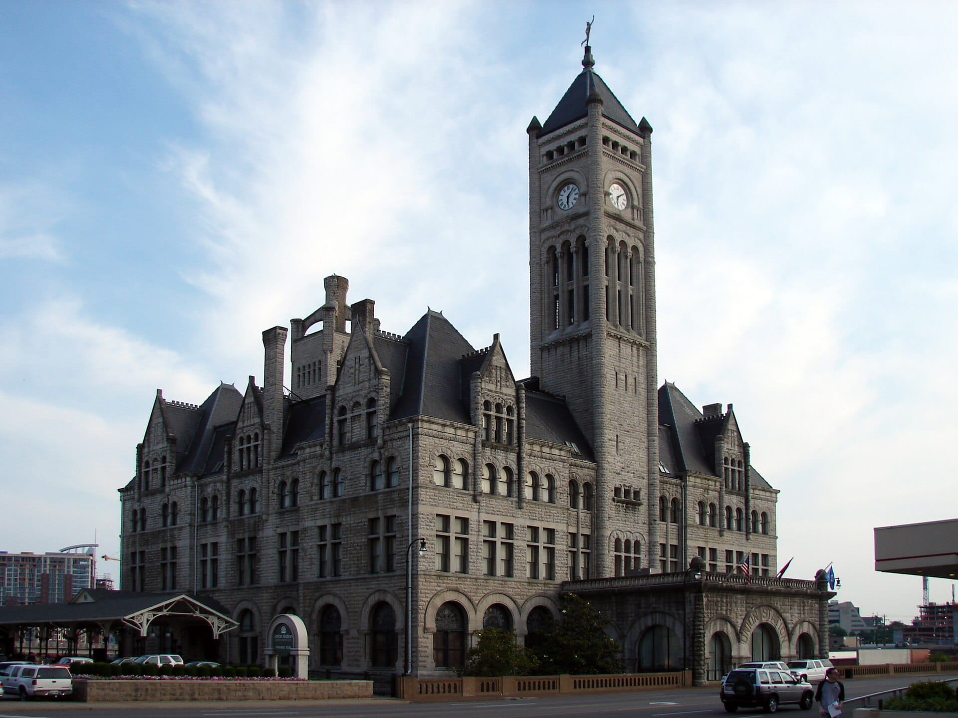 El Union Station Hotel Nashville presenta una llamativa fachada de estilo neogótico con una alta torre del reloj, paredes de piedra caliza y ventanas arqueadas bajo un cielo azul.