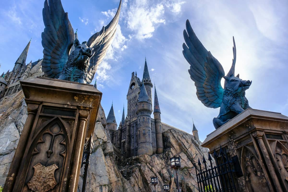 Entrance archway with winged boar statues in front of Hogwarts Castle at Universal's Islands of Adventure on a bright day.
