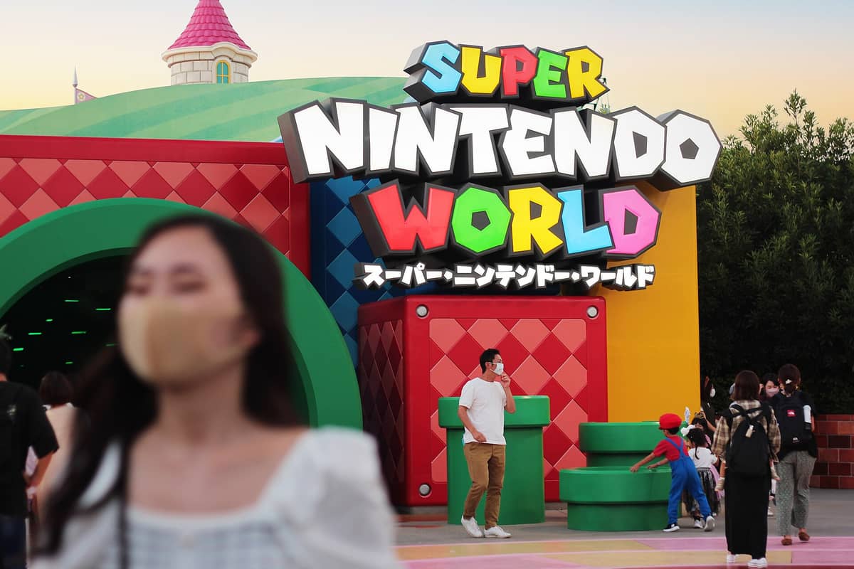 Entrance to SUPER NINTENDO WORLD at Universal Studios Japan, with bright colorful signage and visitors walking around the vivid themed area.