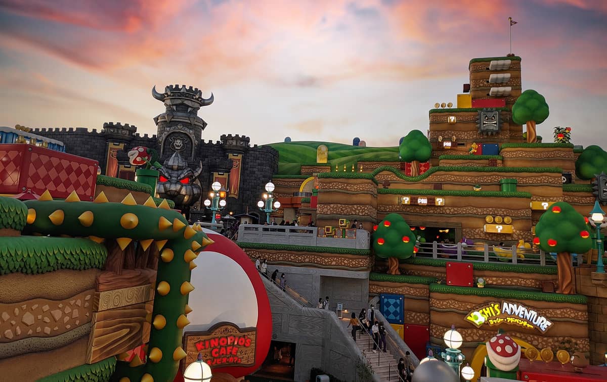 Super Nintendo World area inside Universal Studios Japan at sunset, featuring Bowser’s Castle, Kinopio’s Cafe, Yoshi’s Adventure, and colorful themed scenery.