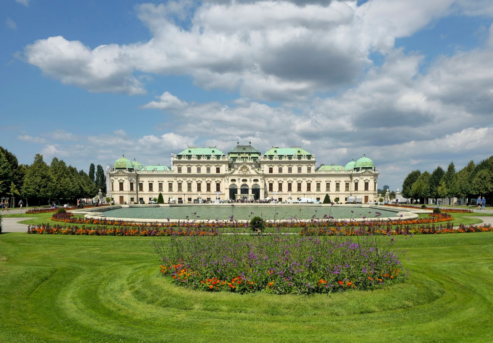 Weitwinkelaufnahme des Oberen Belvedere in Wien mit gepflegten Rasenflächen, runden Blumenbeeten und dramatischem Himmel – ein beeindruckendes Zusammenspiel aus Barockarchitektur und formalem Garten.