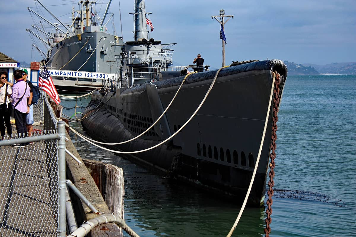 Visitantes en el muelle junto al submarino USS Pampanito, atracado en el Muelle 45 de San Francisco con su nombre visible y la bahía de fondo.