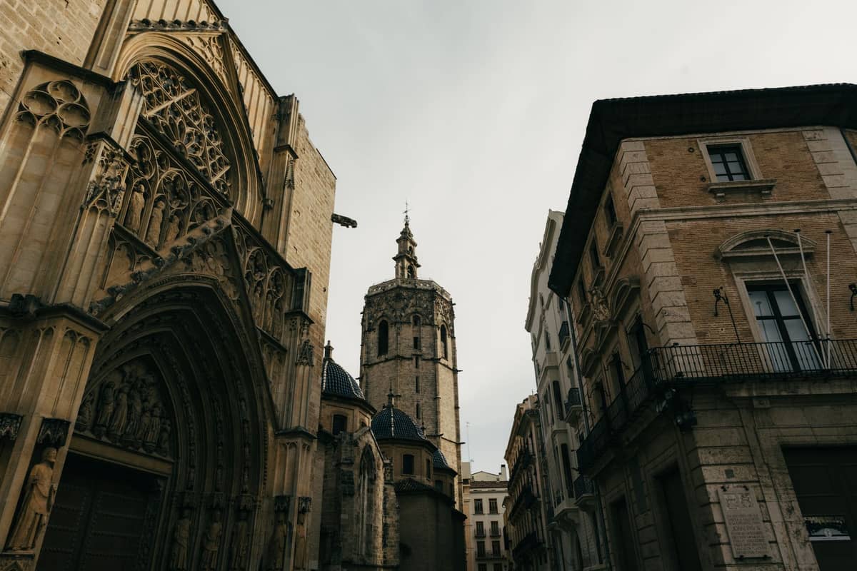 Vista dell'ingresso gotico della Cattedrale di Valencia con il campanile Miguelete e gli edifici storici vicini nel centro storico della città.