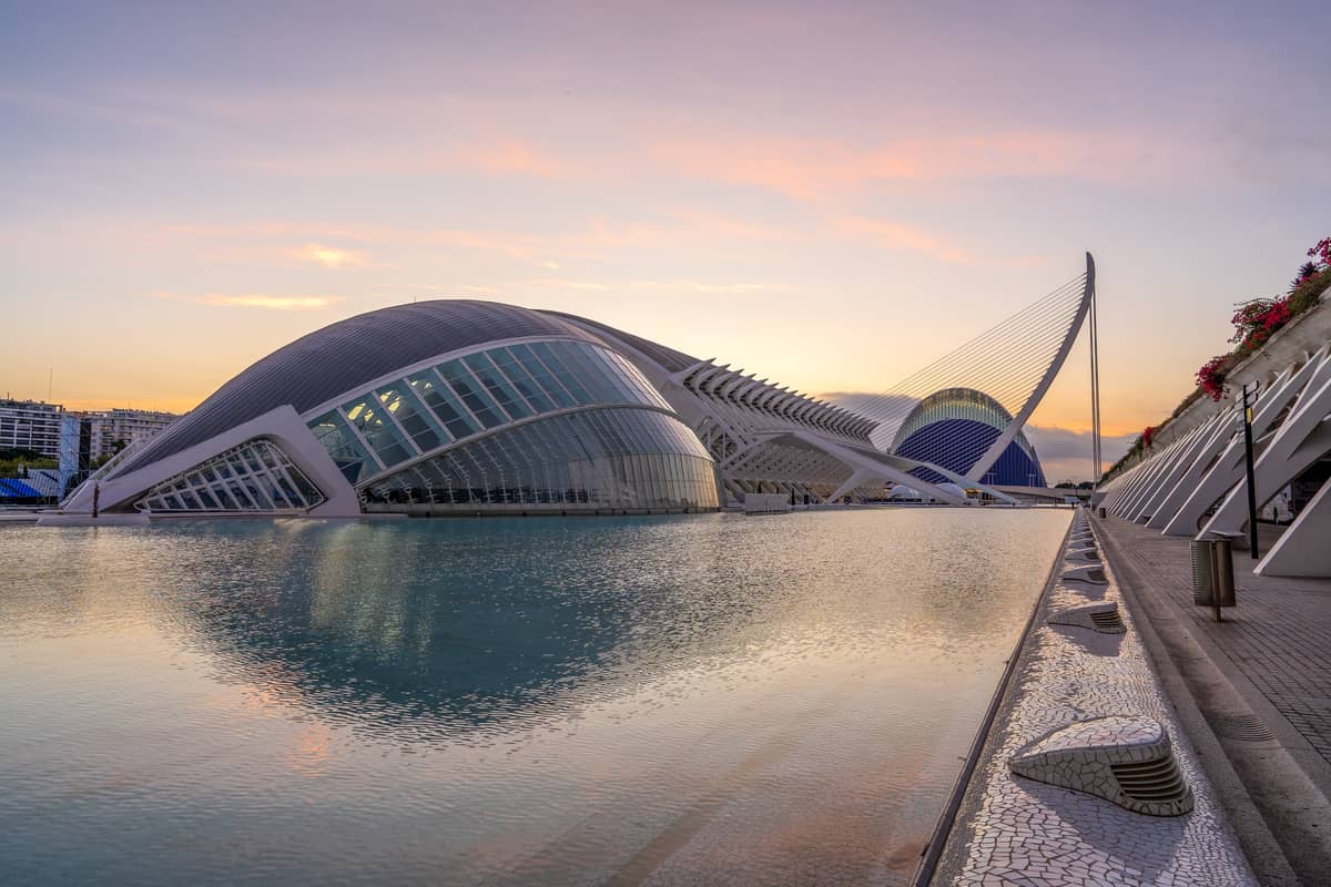 Vista al tramonto della Ciudad de las Artes y las Ciencias a Valencia con architettura moderna riflessa in acque tranquille.