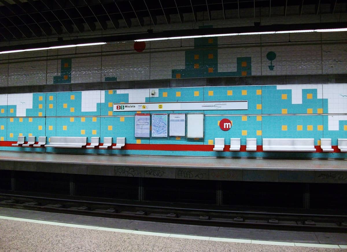 Stazione della metropolitana di Valencia 'Mislata' con piastrelle geometriche blu alle pareti, designazione della linea rossa, panchine e segnaletica chiara delle linee 3 e 5.