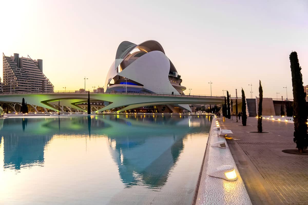 Il Palau de les Arts Reina Sofia e la sua riflessione nell'acqua alla Città delle Arti e delle Scienze di Valencia al tramonto.