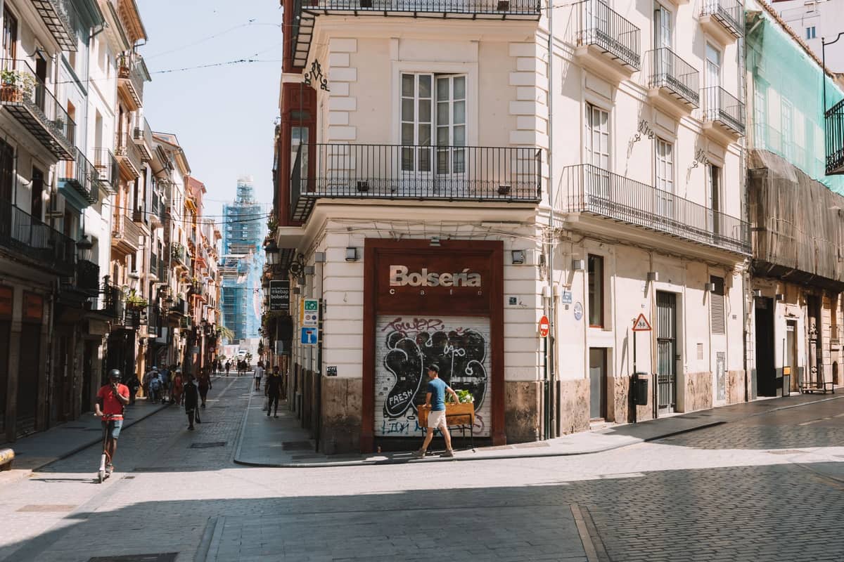 Vista stradale di un edificio angolare a Valencia con appartamenti dall'aspetto conveniente, pedoni e graffiti nel quartiere del centro storico.
