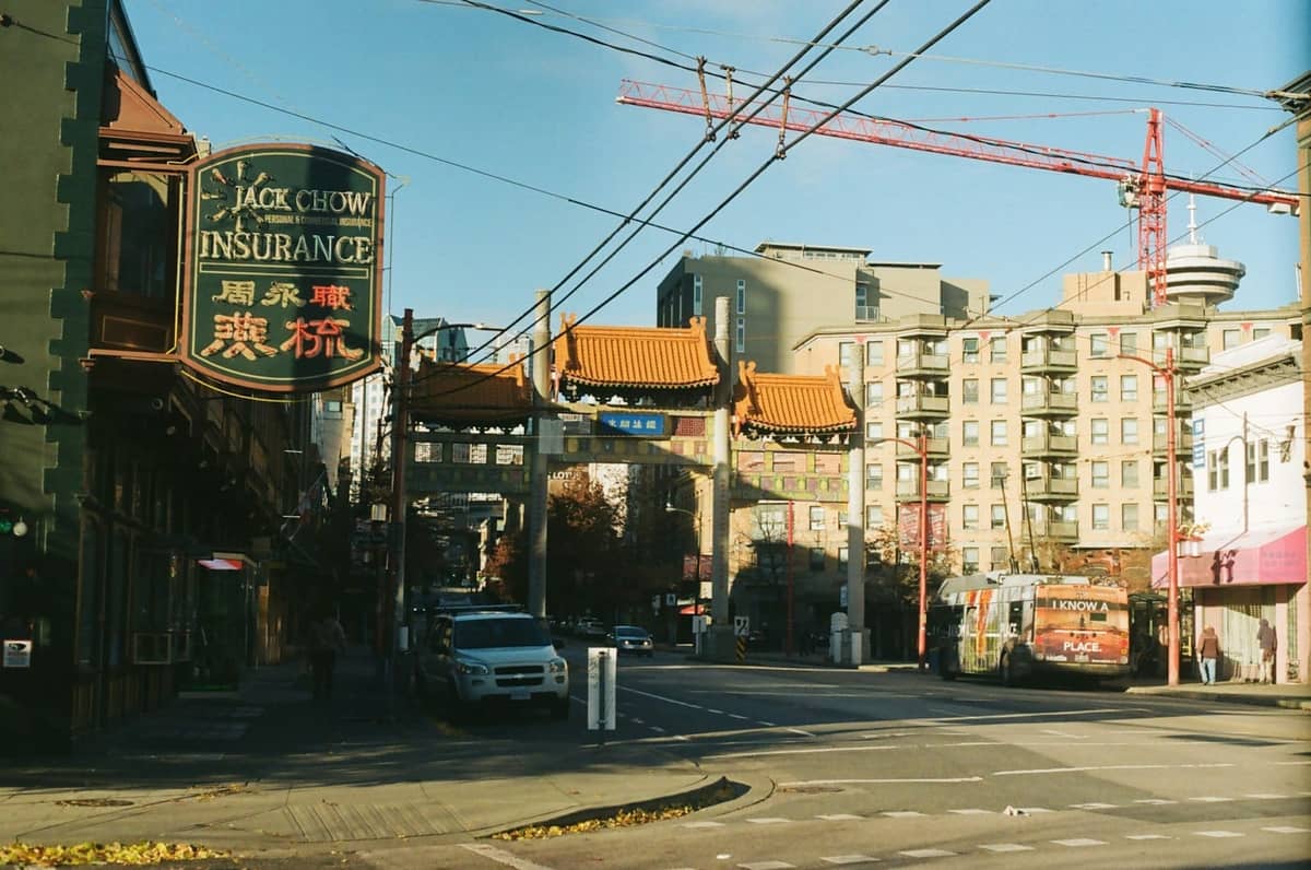 Chinatown Millennium Gate in Vancouver an einem sonnigen Tag, mit nahegelegenen Geschäften und Stadtgebäuden im Blick.