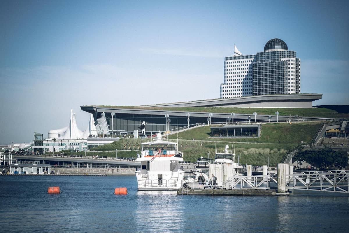 Blick auf das Vancouver Convention Centre mit den Segeln des Canada Place und einem Yachthafen mit Booten im Vordergrund.