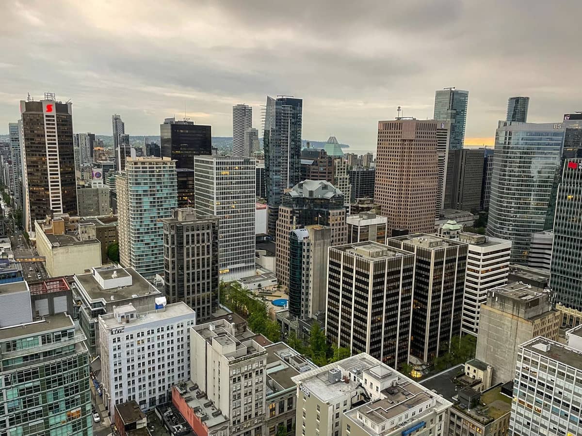 Luftaufnahme der Innenstadt von Vancouver mit dicht gedrängten Wolkenkratzern und Häuserblocks unter einem bewölkten Himmel.