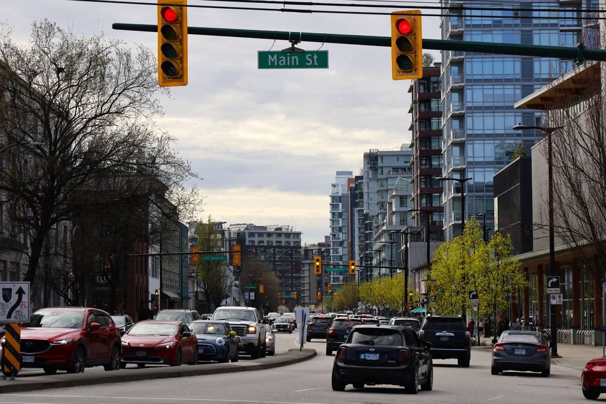 Straßenansicht der Main Street in Vancouver mit Autos, modernen Gebäuden und einem sichtbaren Straßenschild darüber.
