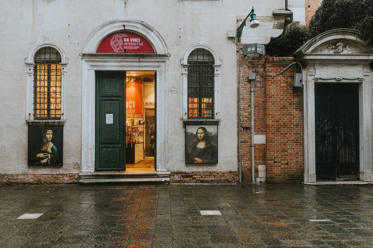 Fassade eines kleinen Kunstmuseums in Venedig mit Gemälden neben dem Eingang und einem Schild über der Tür.