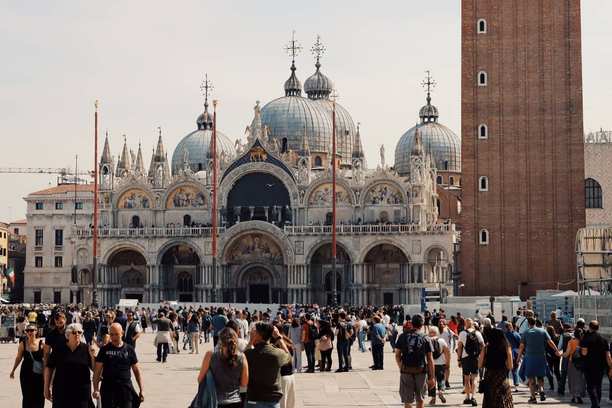 Die überfüllte Piazza San Marco in Venedig mit vielen Touristen vor der Basilika San Marco und dem Campanile an einem sonnigen Tag.