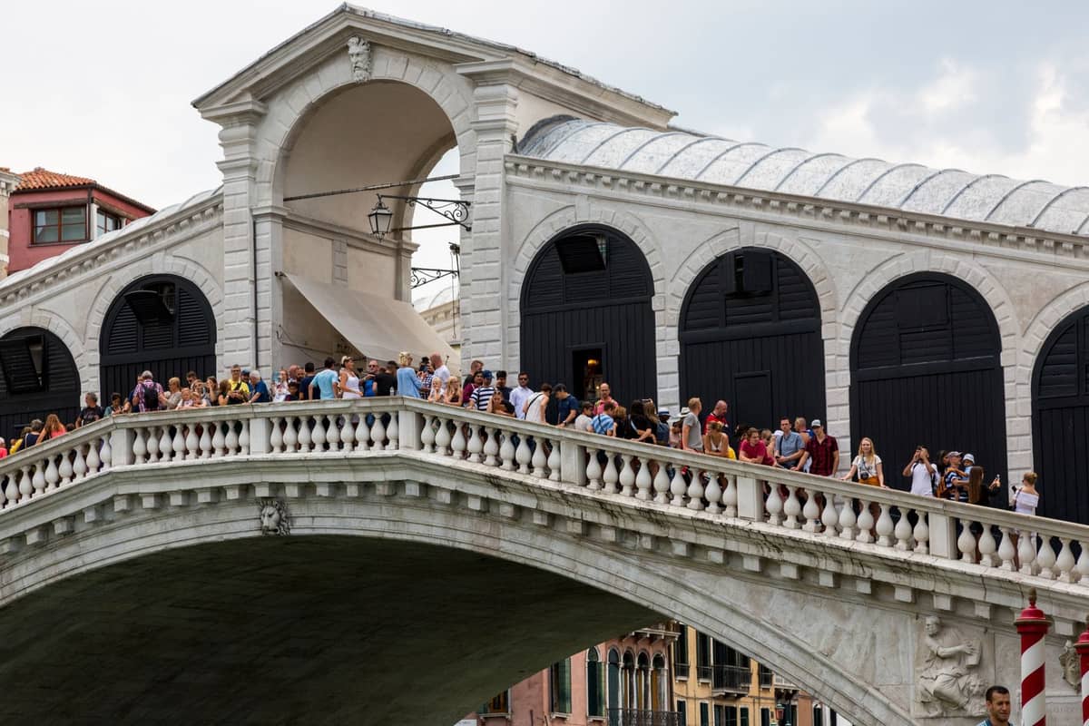 Große Menschenmenge von Touristen entlang der Rialtobrücke in Venedig tagsüber, die die Hauptbesuchszeiten veranschaulicht.