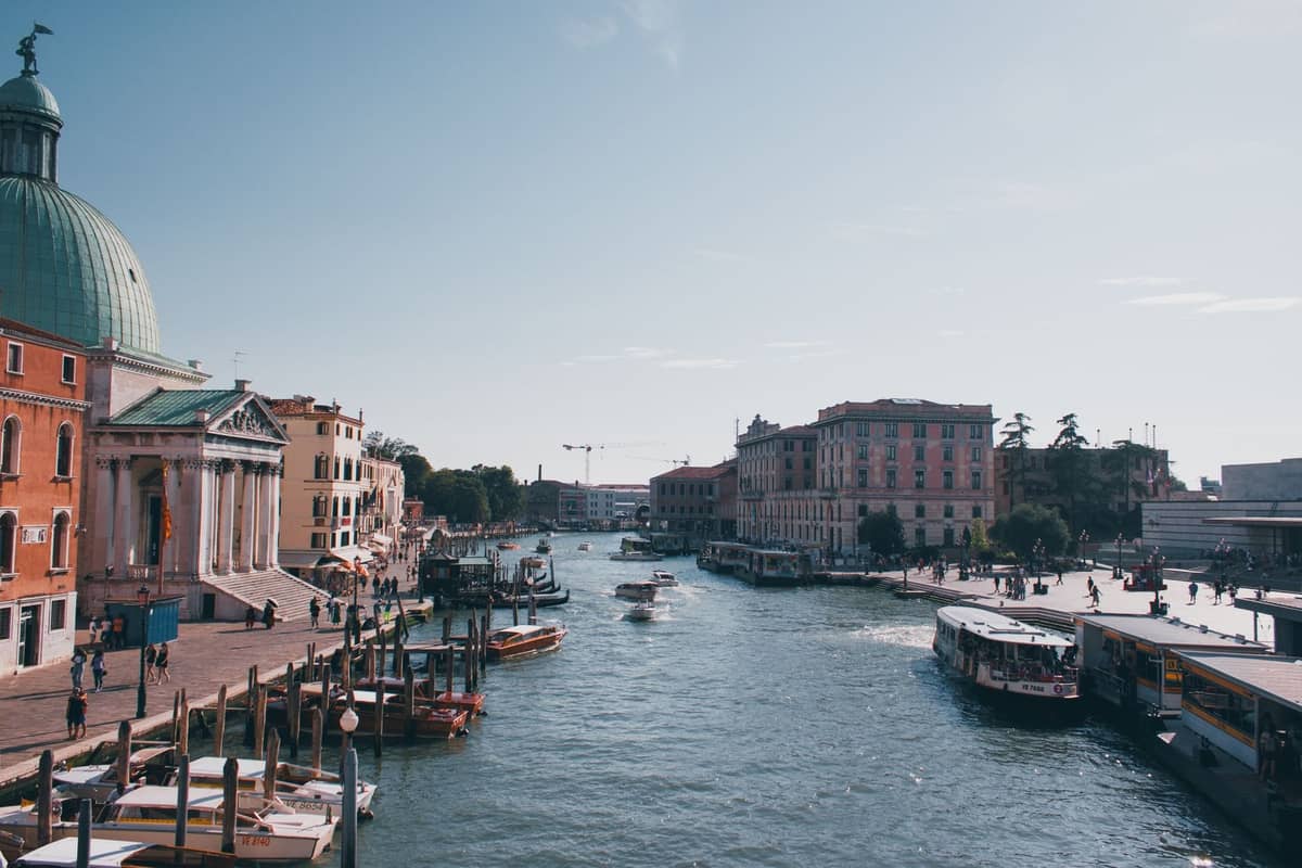 Bereich des Bahnhofs Santa Lucia in Venedig mit dem Canal Grande, Booten, Kirchenkuppel und Gebäuden am Wasser an einem sonnigen Tag