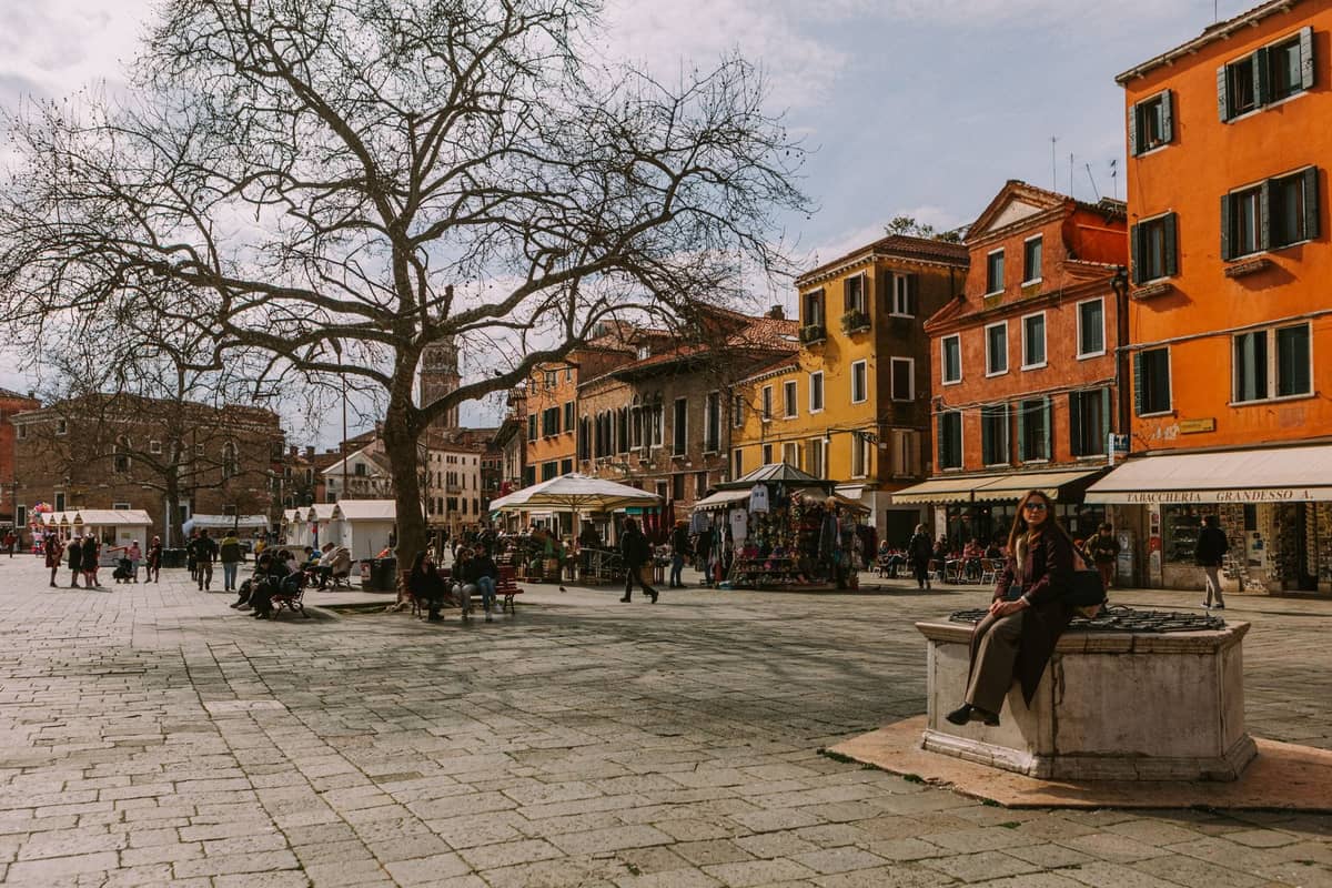 Weiter venezianischer Platz mit Einheimischen und Familien, bunten historischen Gebäuden und Marktständen, der die ruhigen Viertel widerspiegelt, in denen Familien in Venedig übernachten können.