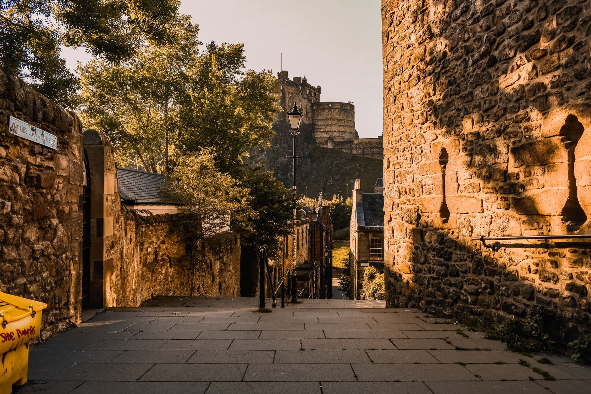 Die Steinstufen des Vennel führen hinauf zu Edinburgh Castle, eingerahmt von historischen Steinmauern und Gebäuden im warmen Abendlicht.