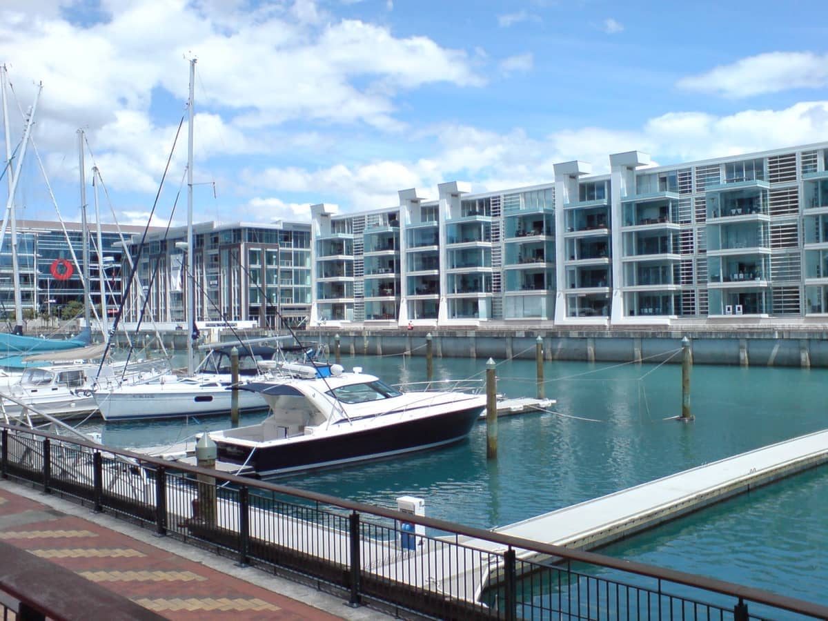 Moderne Apartments und festgemachte Yachten am Viaduct Harbour, Auckland, mit klarem blauem Wasser und sonnigem Himmel.
