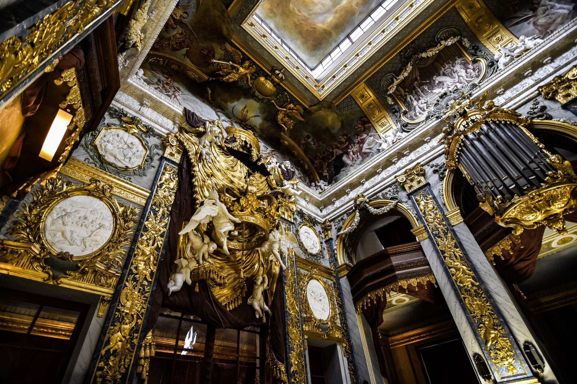 Prunkvoll verziertes Barockinterieur mit goldenen Details, imposanten Skulpturen und einer dekorierten Decke in einem historischen Wiener Gebäude.
