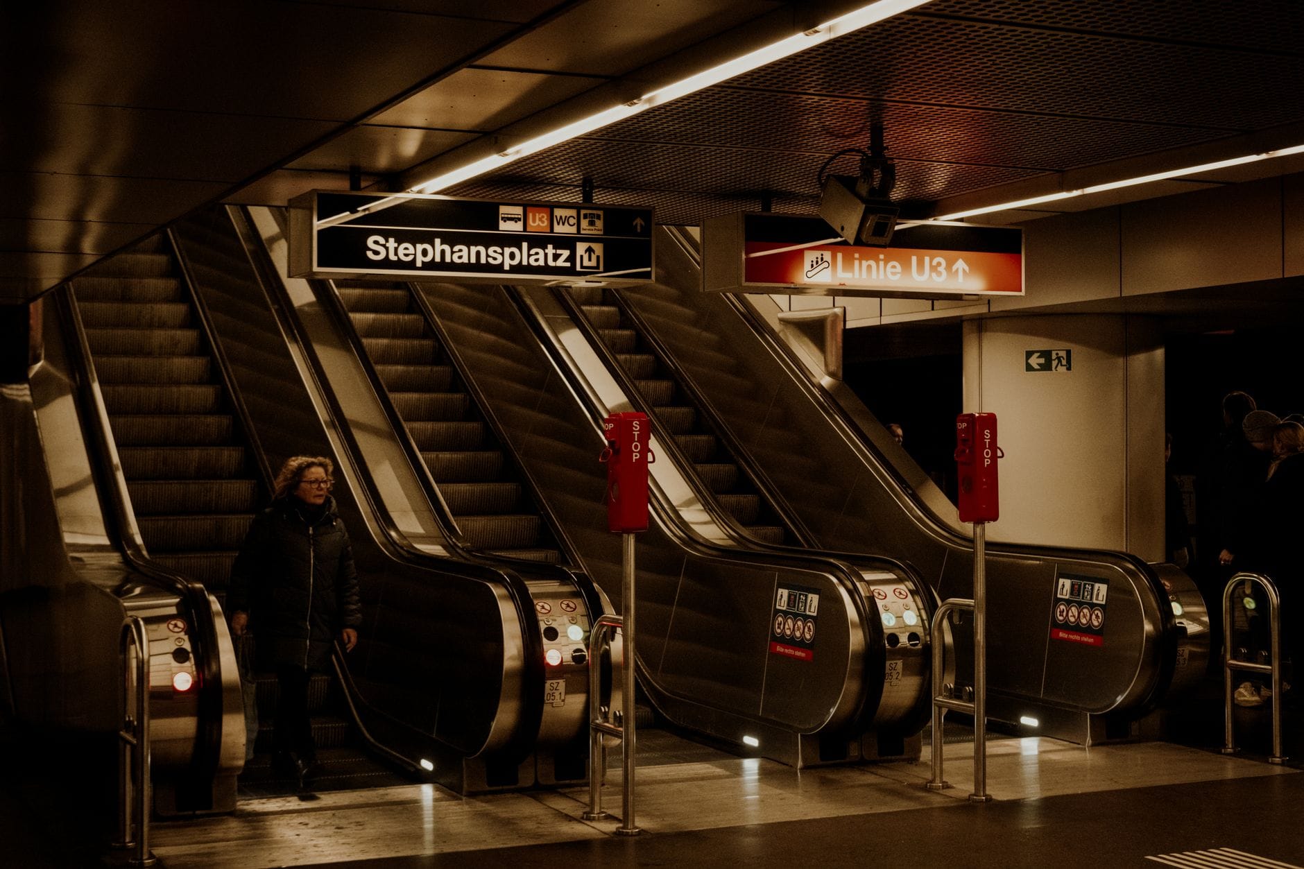 Rolltreppen der U-Bahn-Station Stephansplatz Wien mit klaren Richtungsschildern und einer Person auf der Rolltreppe.