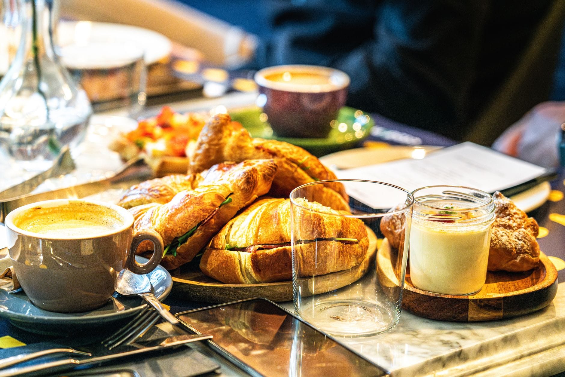 Caffè in una tazza tradizionale con dolci e un croissant su un tavolo in un accogliente caffè, che evoca l'atmosfera di una Kaffehaus di Vienna.