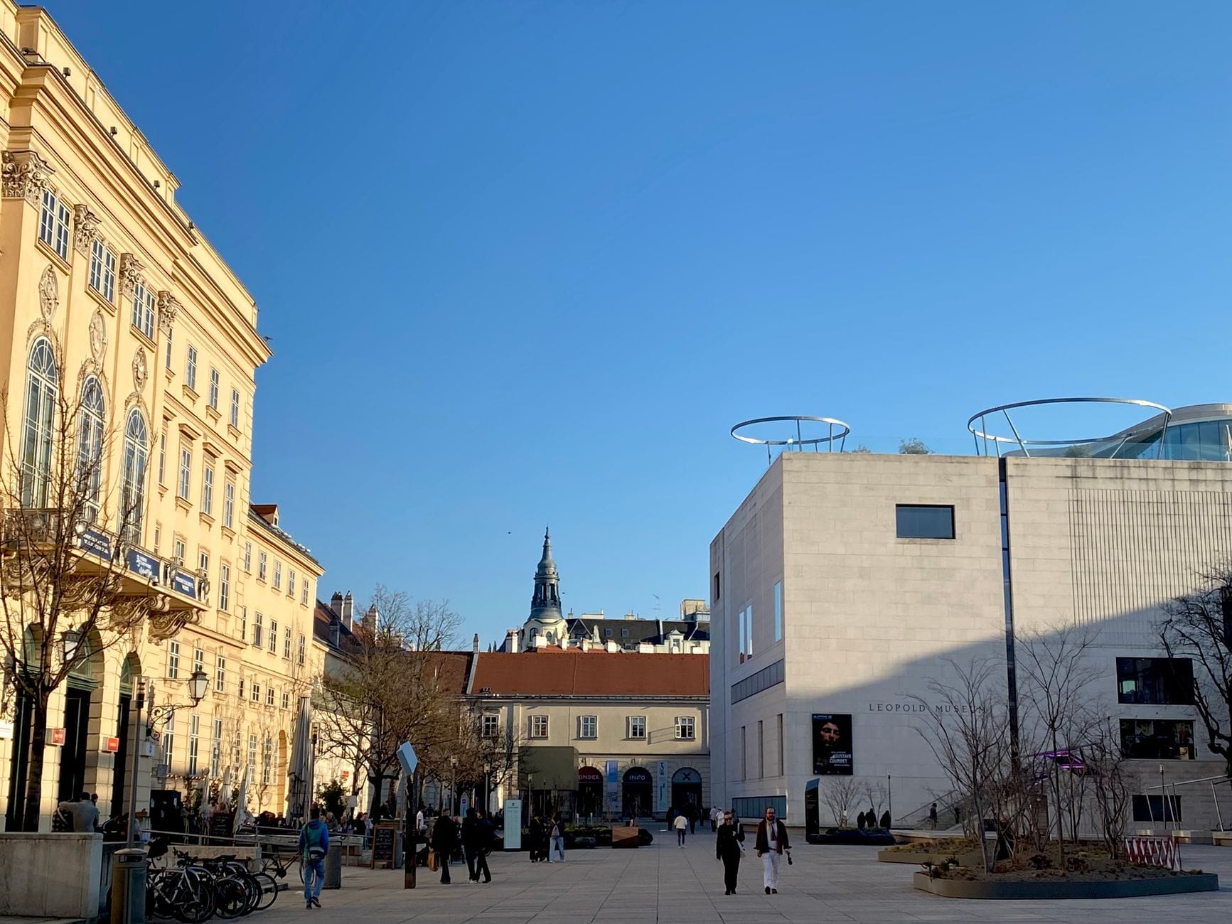 Современное белое кубическое здание Leopold Museum с прогуливающимися людьми на ярком солнце в MuseumsQuartier Вена
