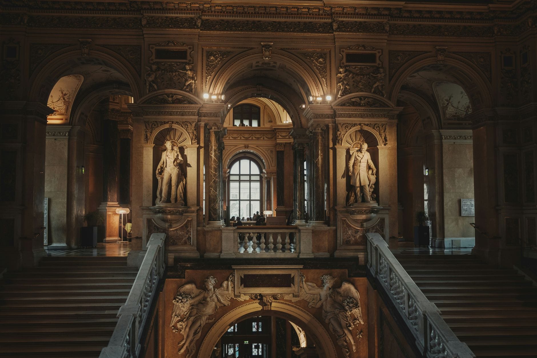 Grande scalinata e statue all'interno di una sontuosamente decorata istituzione culturale viennese, che invita i visitatori a esplorare la ricca cultura interna di Vienna.
