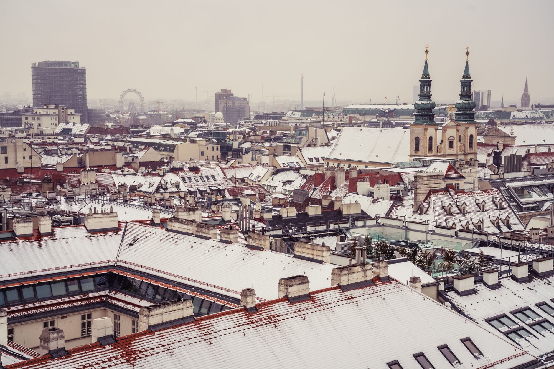 Tetti innevati e edifici storici a Vienna sotto un cielo invernale coperto.
