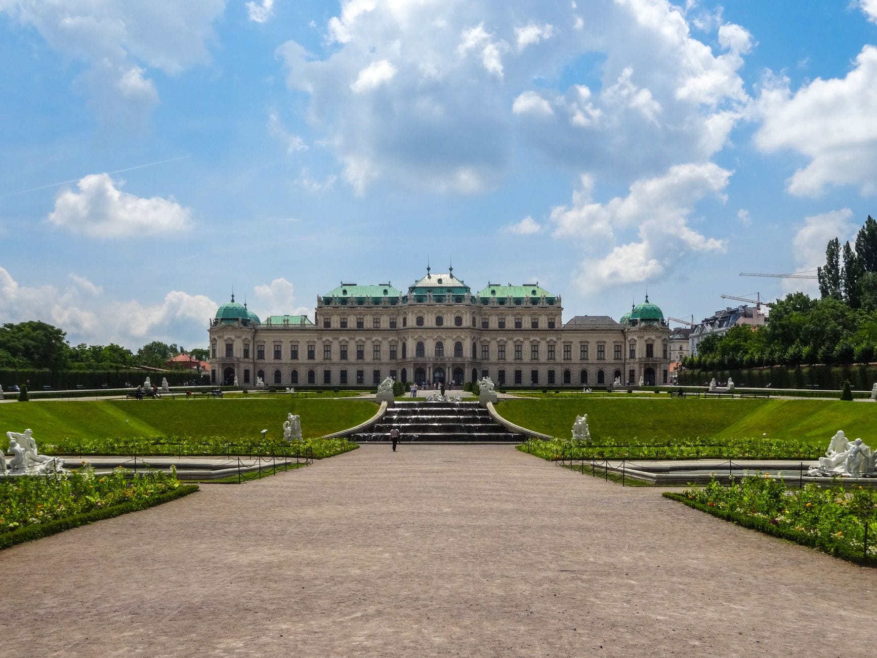 Vista amplia del Palacio Belvedere en Viena con jardines simétricos y estatuas en un día soleado, destacando una importante atracción de pago.
