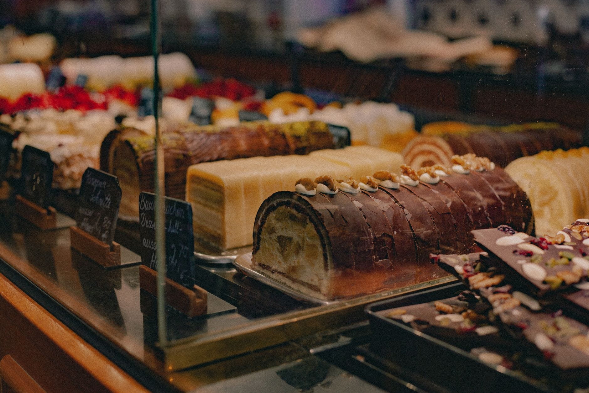 Vitrine einer Wiener Konditorei mit mehreren Torten und Schokoladendesserts, darunter schokoladenüberzogene Kuchen mit Nüssen.