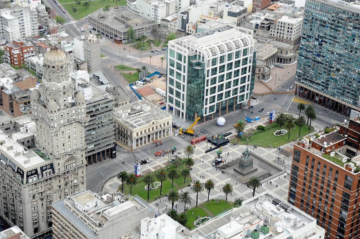 มุมมองทางอากาศของ Plaza Independencia ในมอนเตวิเดโอ พร้อมด้วย Palacio Salvo ที่โดดเด่น อาคารสมัยใหม่และอาคารประวัติศาสตร์โดยรอบ ต้นปาล์ม และอนุสาวรีย์ Artigas ที่ตั้งอยู่ตรงกลาง