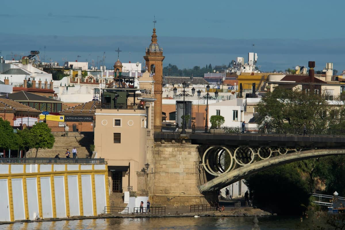 สะพาน Puente de Isabel II ข้ามแม่น้ำ Guadalquivir พร้อมอาคารในย่าน Triana และหอคอยโบสถ์ในเมือง Seville