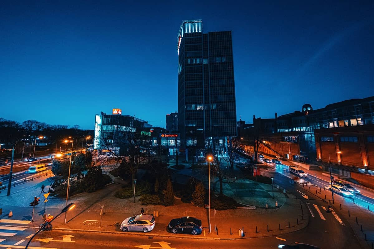 Paesaggio urbano notturno con una torre distintiva, rotatorie e strade illuminate nel quartiere di Praga a Varsavia.