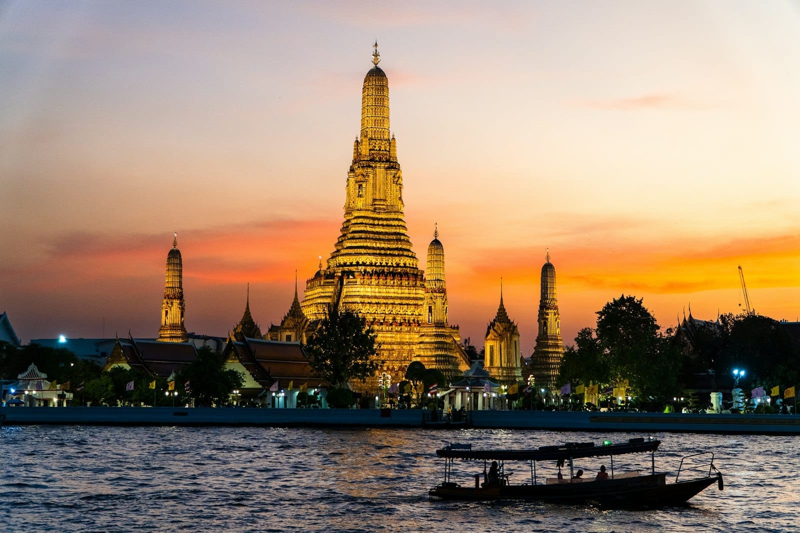 Wat Arun al tramonto visto dal fiume Chao Phraya a Bangkok con una barca tradizionale in primo piano