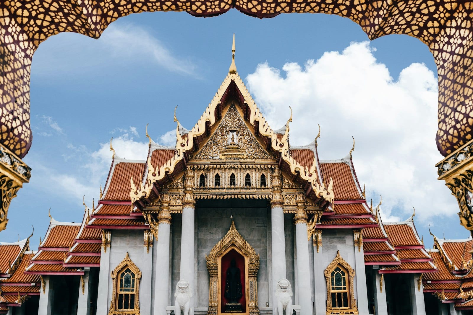 Il maestoso tempio Wat Benchamabophit a Bangkok con la facciata in marmo bianco di Carrara, i tetti ornamentali a più livelli e le statue di leoni guardiani all'ingresso.