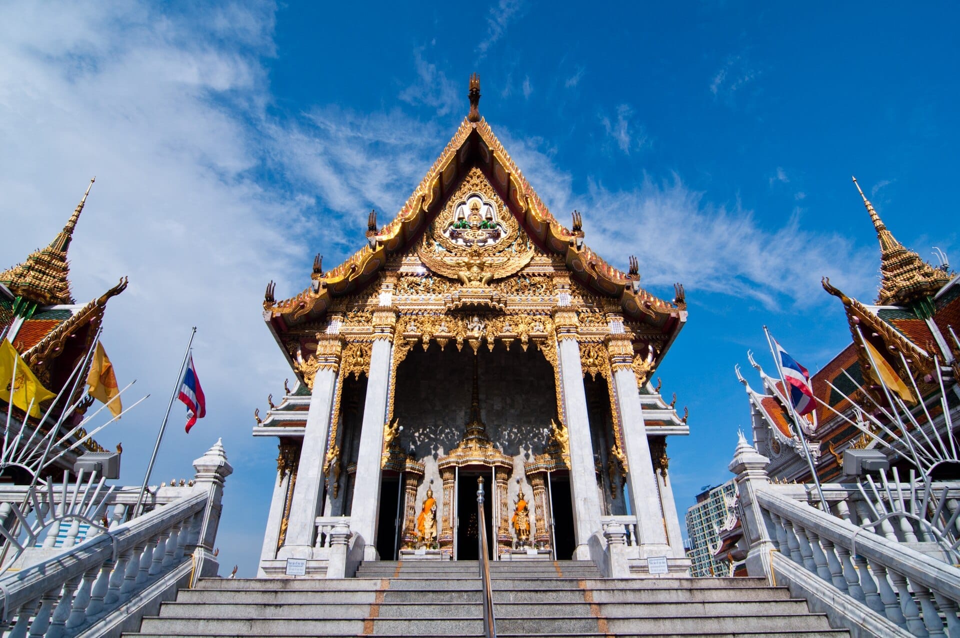 Ingresso del tempio Wat Hua Lamphong a Bangkok con facciata dorata ornata e bandiere thailandesi