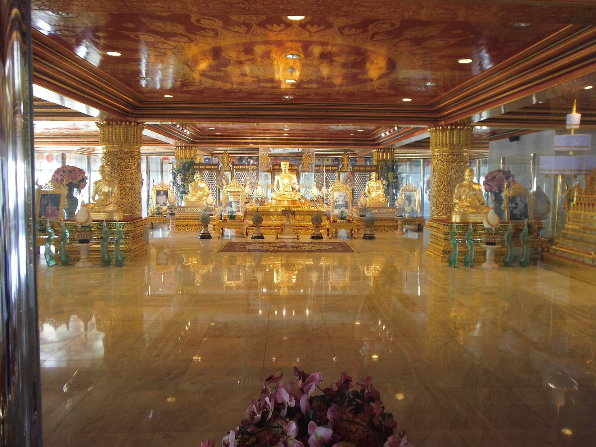 Sala interna dorata del Wat Paknam Phasi Charoen a Bangkok con statue di Buddha e decorazioni ornamentali tipiche dei templi thailandesi